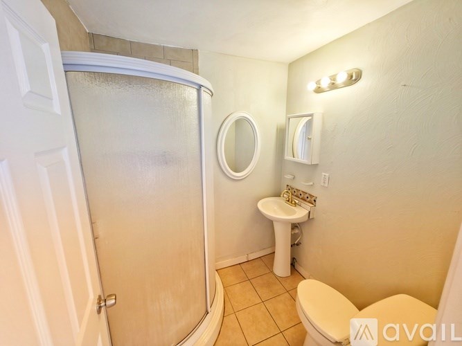 A small bathroom with a toilet, sink, and shower.