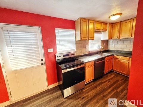 A kitchen with red walls and wooden cabinets.
