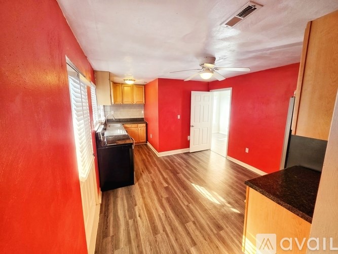 A room with red walls and wooden flooring is available for rent.