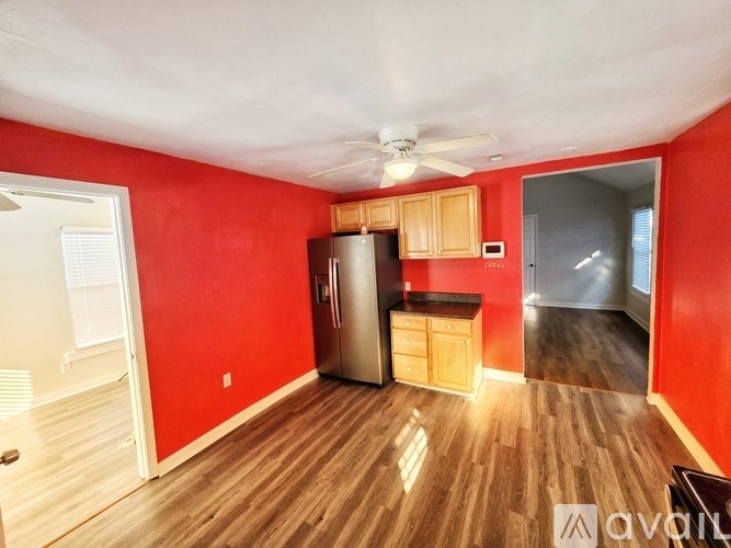 A kitchen with red walls and wooden floors is available for rent.