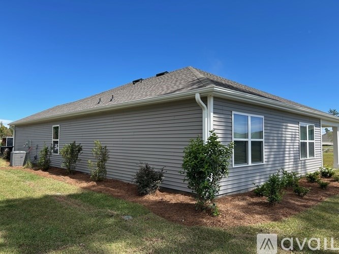 A house with a grey siding and a brown roof with a small garden in front.