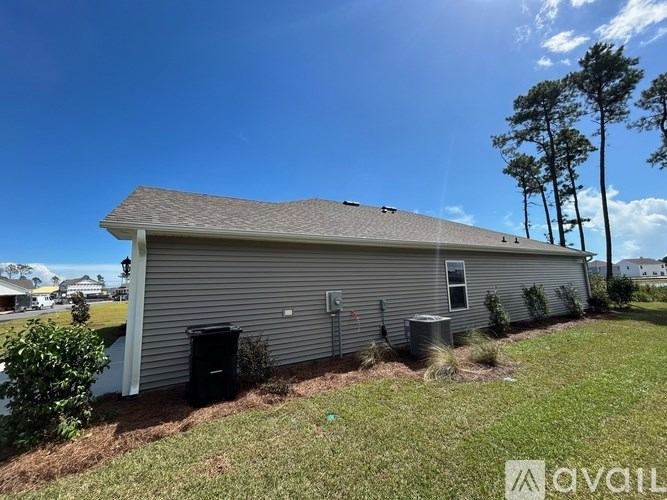 A house with a gray roof and a black trash can in front of it.