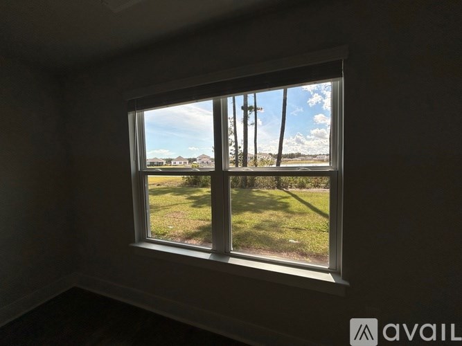 A window with a view of a grassy field and utility poles.