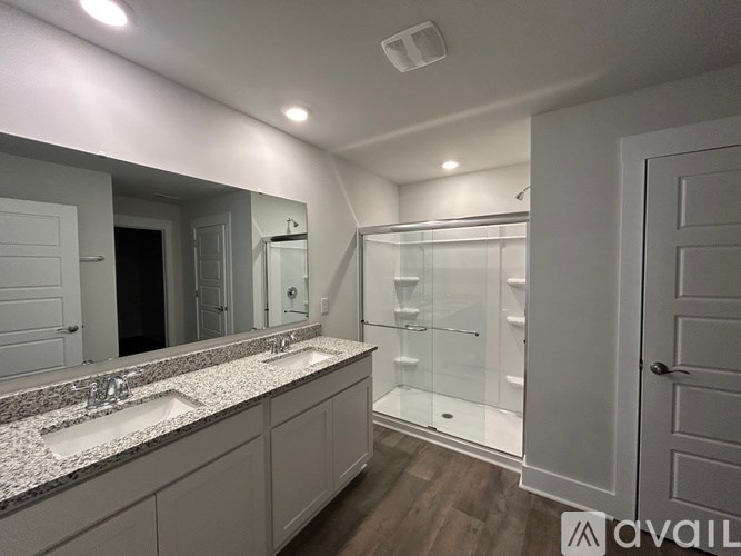A bathroom with a double sink vanity and a walk-in shower.