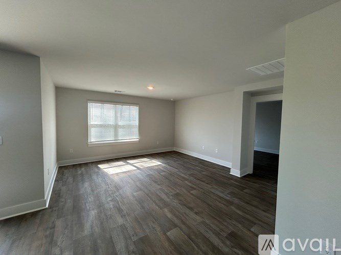 A room with wooden flooring and a window with blinds.