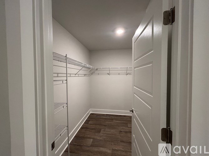 A walk-in closet with white shelves and a wooden floor.