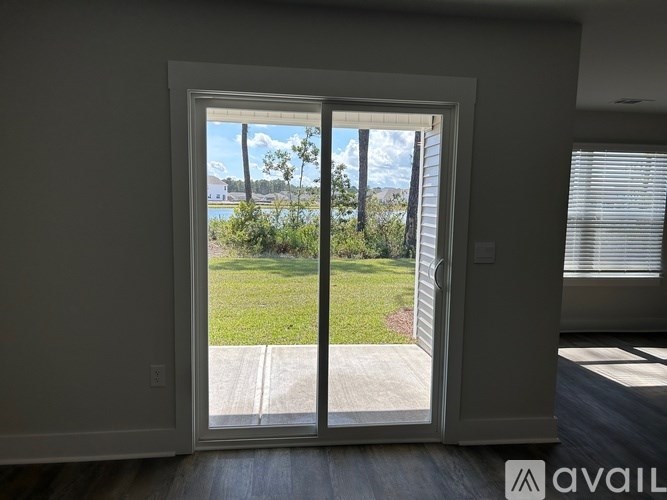 A sliding glass door opens to a backyard with a lawn and trees.