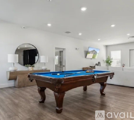 A pool table is in the middle of a room with a mirror and picture on the wall.