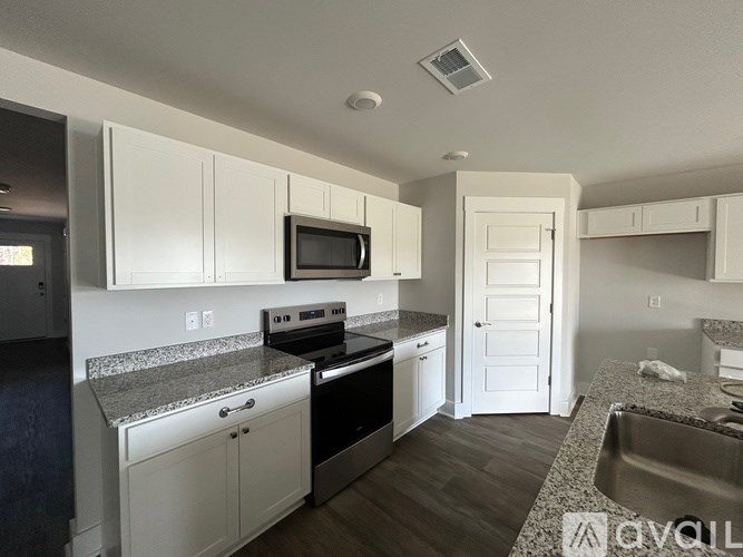 A kitchen with white cabinets and a granite countertop.