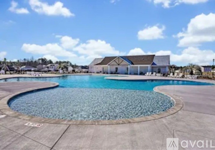 A large outdoor swimming pool with a tiled edge and a building in the background.