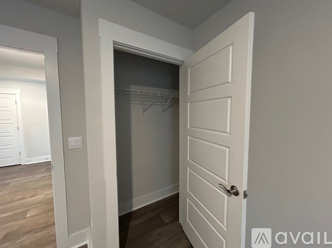 A white door with a handle is open to a room with a closet.