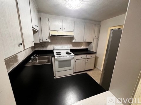 A kitchen with white cabinets and black countertops.