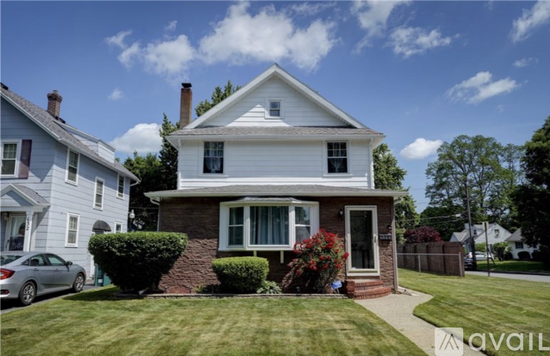 A white house with a red door and a small front yard.