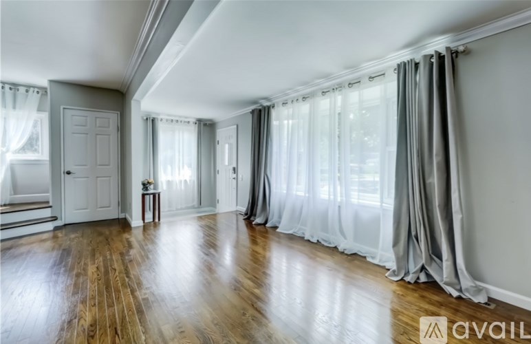 A room with wooden floors and white curtains.