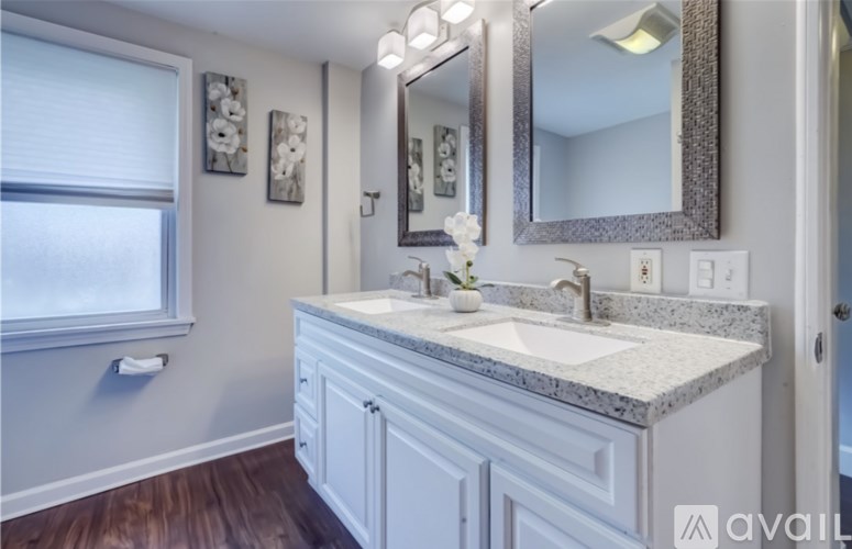 A bathroom with a sink, mirror, and two framed pictures on the wall.