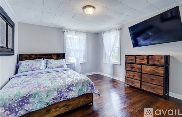 A bedroom with a bed, dresser, and television.