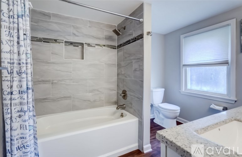 A bathroom with a white tub and a window.