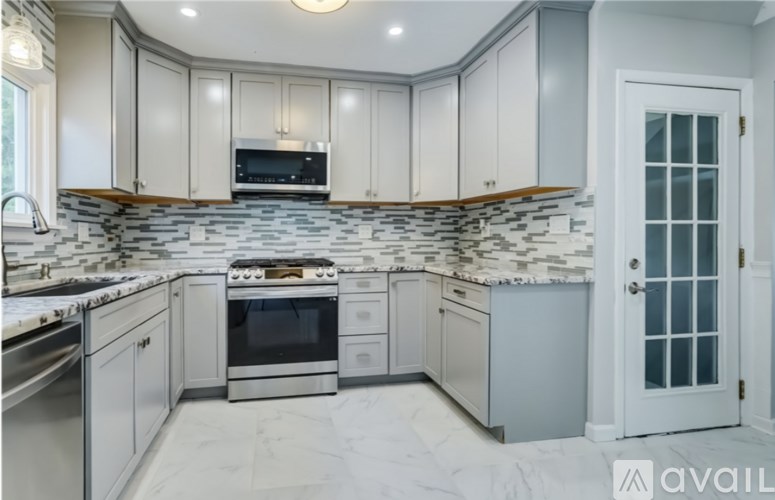 A kitchen with white cabinets and a stone backsplash.