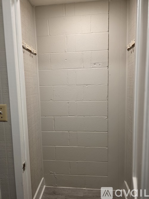 A white bathroom with a white tiled shower wall.
