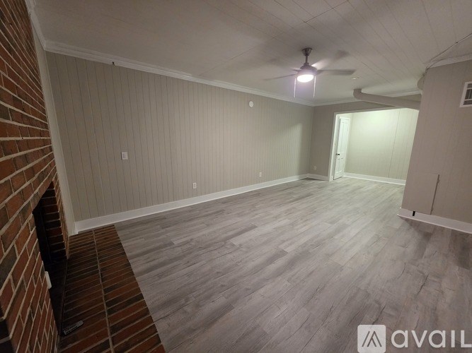 A room with a ceiling fan and wooden flooring.