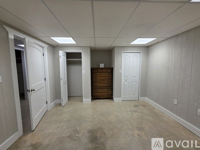 A room with white walls and a wooden dresser in the middle.