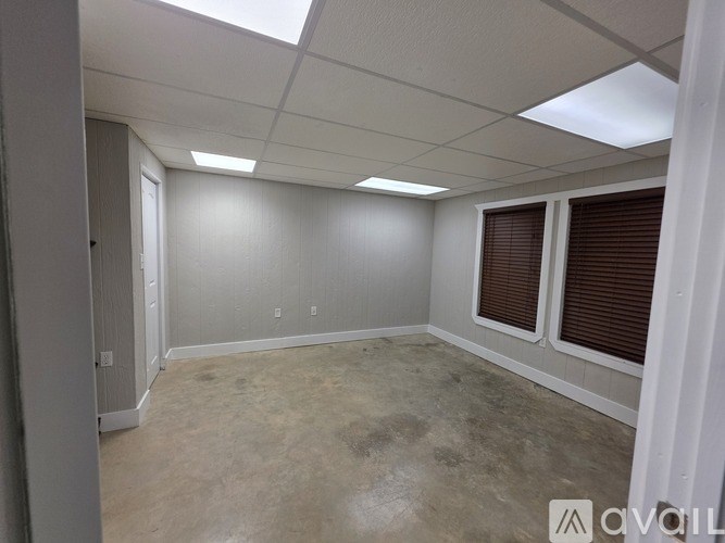 A room with a white ceiling and a window with brown blinds.