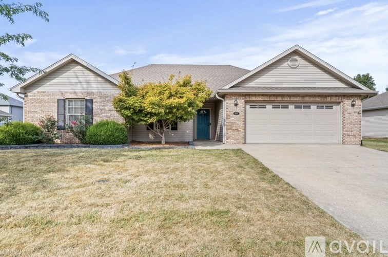 A house with a garage and a tree in front.