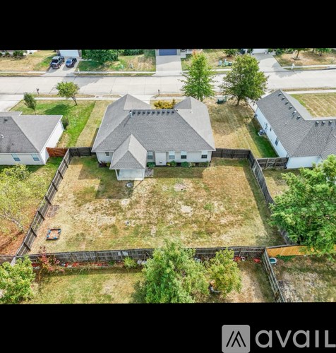 A bird's eye view of a residential area with houses and a fenced yard.