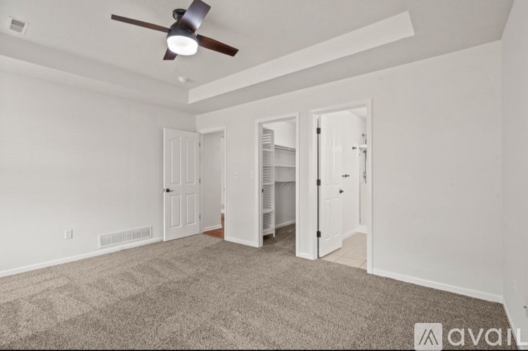 A room with a ceiling fan and carpeted floor.