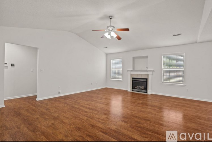 A spacious room with a fireplace and wooden flooring.