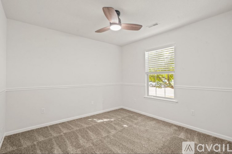 A room with a ceiling fan and a window with blinds.