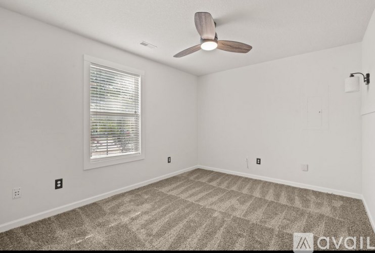 A room with a ceiling fan and a window with blinds.