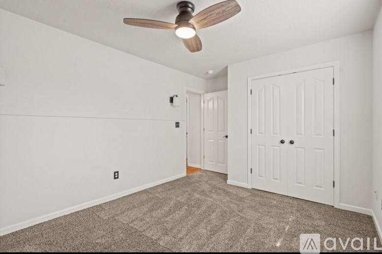 A room with a ceiling fan and two doors.