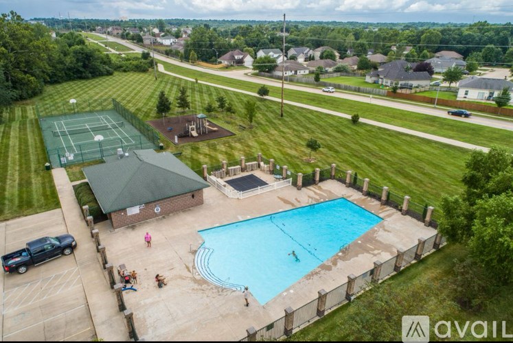 A pool with a slide and a tennis court with people playing tennis.