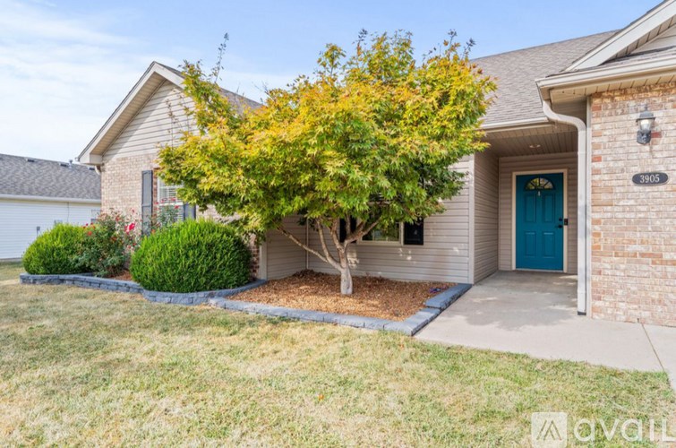 A house with a blue door and a tree in front.