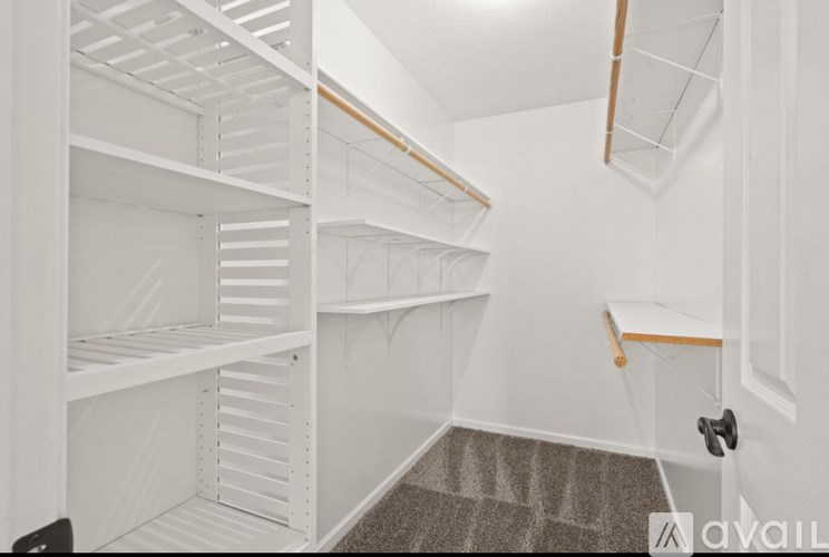 A white room with a carpeted floor and a door on the right.