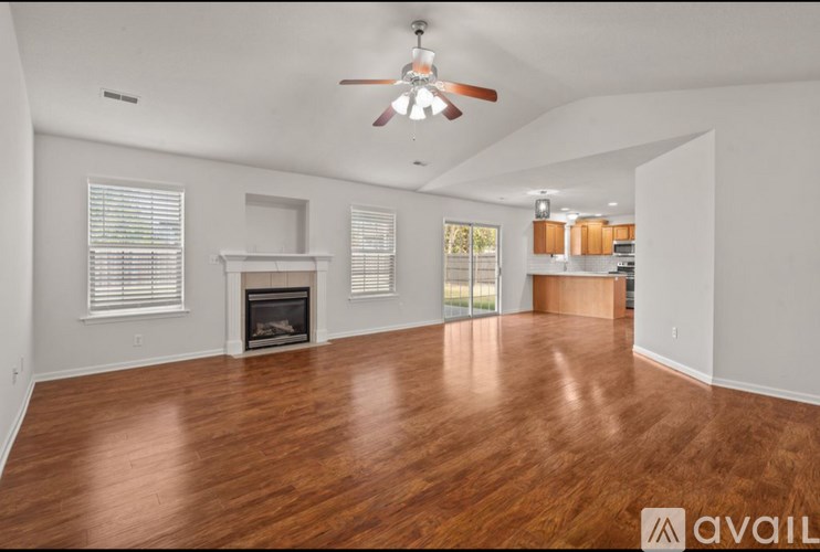 A spacious room with a fireplace and wooden flooring.