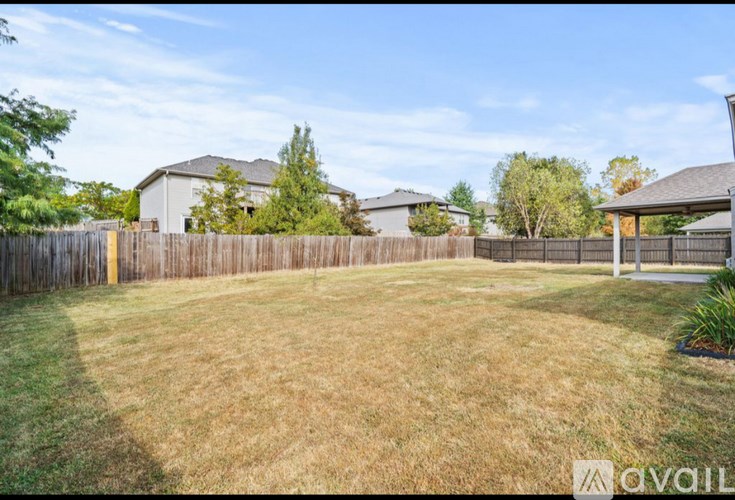 A backyard with a fence and a house in the background.