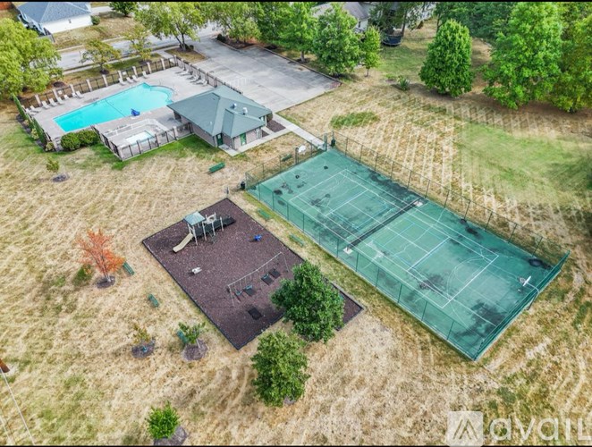 An aerial view of a tennis court and a basketball court surrounded by trees and a swimming pool.