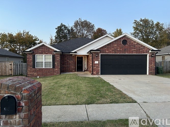 A brick house with a black garage door and a mailbox on the left.