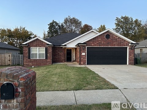 A brick house with a black garage door and a mailbox on the left.