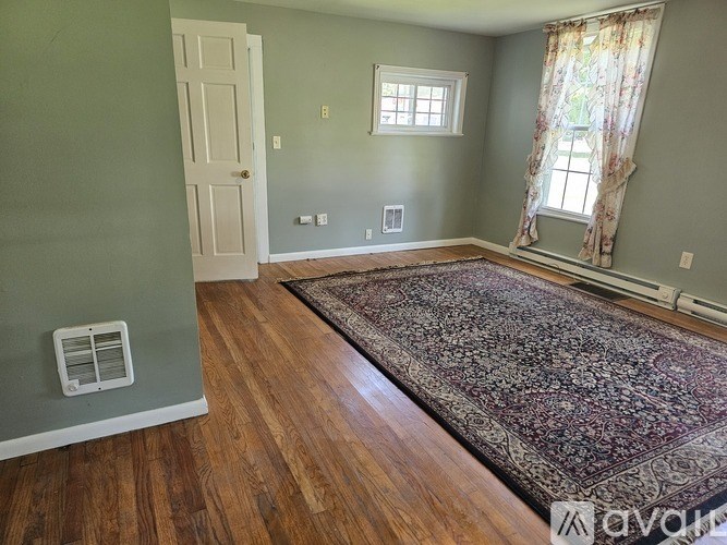 A room with a rug, a window, and a door.