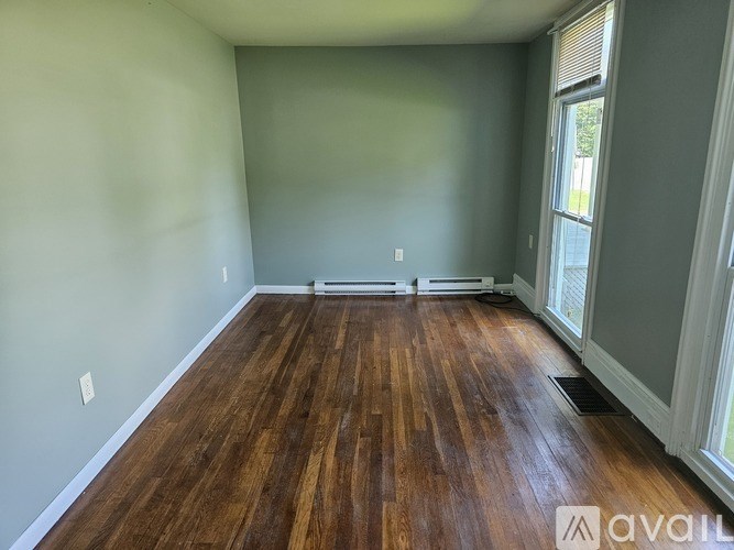 A room with wooden flooring and white walls is available for rent.