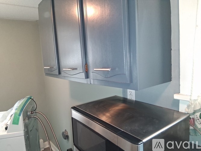 A kitchen with grey cabinets and a stainless steel microwave.
