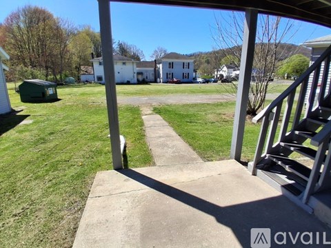 A view from a porch looking out at a grassy yard and houses.