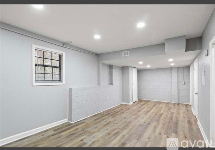 A spacious room with wooden flooring and white walls.