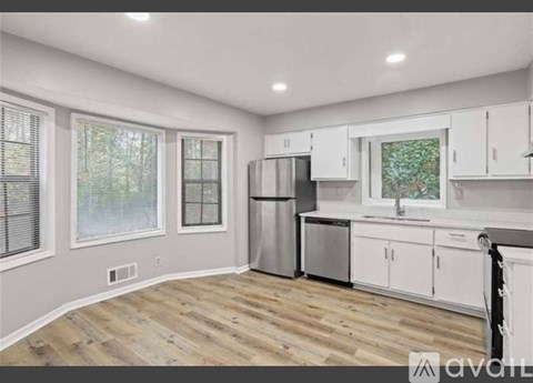 A kitchen with white cabinets and a wooden floor.