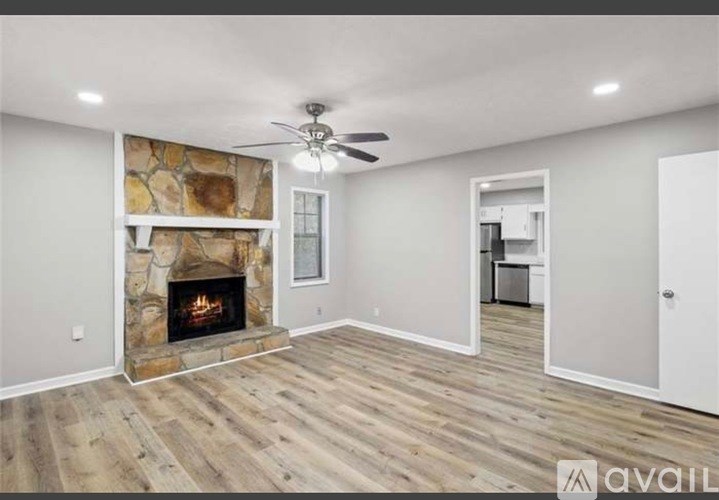 A living room with a stone fireplace and wood flooring.
