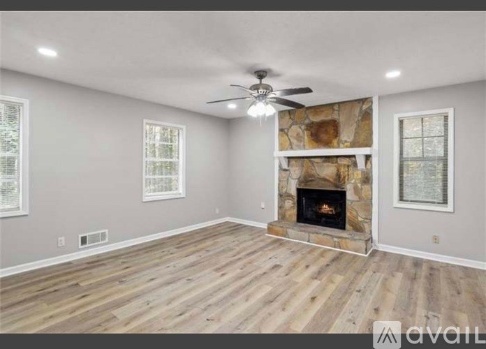A spacious living room with a fireplace and a ceiling fan.