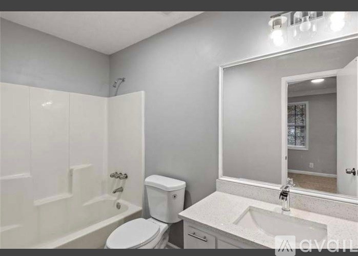 A white bathroom with a toilet, sink, and mirror.